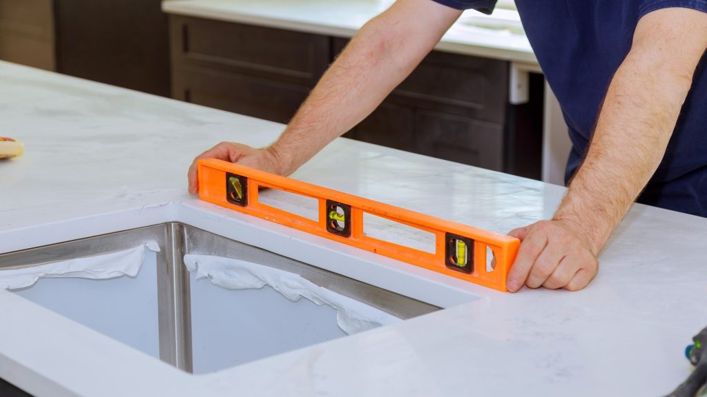 Installer measuring a newly installed kitchen cabinet run for a custom stone countertop template