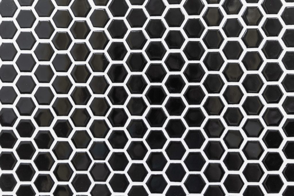 Glazed black hexagon mosaic tile set with bright white grout, where the contrasting joints outline every individual tile